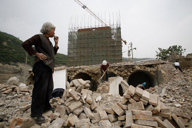 Villagers work to salvage bricks and metal for scrap at a site where traditional cave dwellings are being demolished and  new apartments being built near Yanan in rural Shaanxi Province.