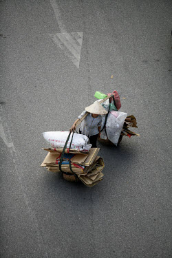 Woman carrying cardboard and paper for recycling.