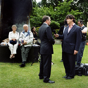 Tourists look on as Conservative MP Dr Liam Fox talks to the BBC in Abingdon Street Gardens on the day Gordon Brown took over as British Prime Minister. Abingdon Street Gardens, often referred to as C...