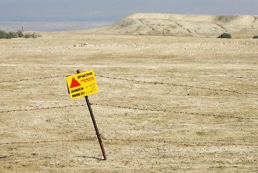 A danger sign warning of mines is attached to a barbed wire fence in the Jordan Valley. The Jordan River area is highly militarised and protected by mine fields.