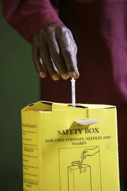 A health worker following correct safety procedures in disposing a used syringe in a safety box.