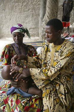 A health worker giving oral vaccination drops to a baby at an outdoor clinic.