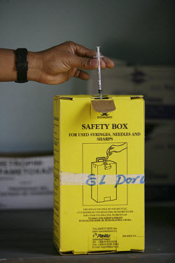 Disposing of a syringe in a safety box at El Porvenir Health Unit.