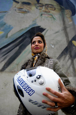 A portrait of Laleh Seddigh with her crash helmet below a billboard depicting Iran's Supreme Leader Ayatollah Ali Khamenei (right) and Ayatollah Khomeini (left). Seddigh is Iran's best female racing c...