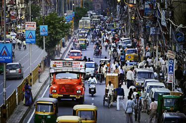 Cars compete with motorised auto-rickshaws, bicycle rickshaws, buses and trucks for space on a busy road.