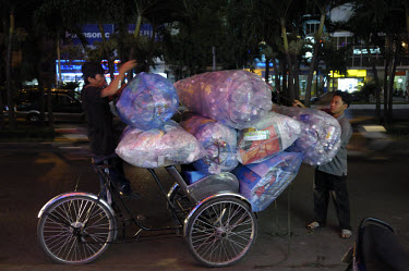 A cyclo loaded to the brim with plastic bottles for recycling.