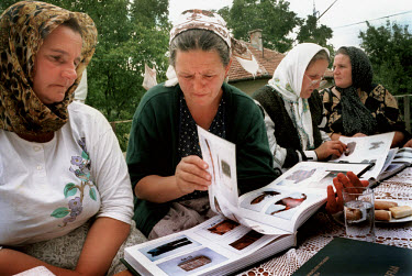 Women from Srebrenica look through an identification book produced by the Red Cross for traces of their menfolk, who disapeared without trace during the Serb attack on the town in 1995. The book conta...