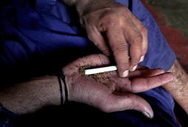 A worker making a marijuana cigarette in his quarters in the ship-breaking yard in Gaddani.