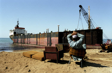 A manager sits back on his chair as a ship is dismantled in the Gaddani ship-breaking yard. In the days when Gaddani was still in full operation it wasn't uncommon to find hundreds of ships here, all...