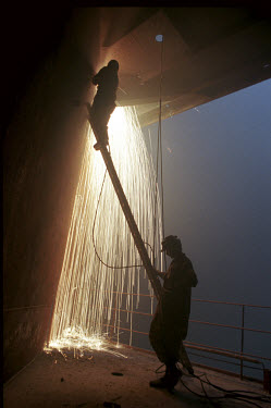 A worker holds a ladder for the welders working above in the ship-breaking yard in Gaddani.