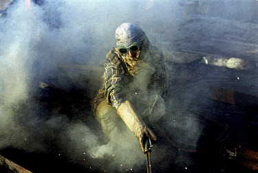 A worker welds a large piece of metal in the ship-breaking yard in Gaddani.