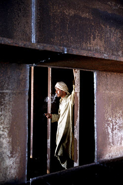 A worker has a smoke during a break at the ship-breaking yard in Gaddani.