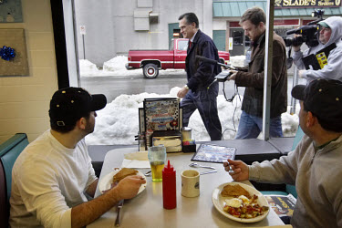 Customers at Norton's Diner watch Mitt Romney, Republican candidate for President, walking by with reporters in tow during the New Hampshire primary campaign.