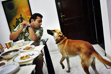 Raman Verma talks to his pet dog as he eats brunch with his family. Raman attended a cooking class the day before in an effort to improve his family's nutrition which depends heavily on take-out, frie...