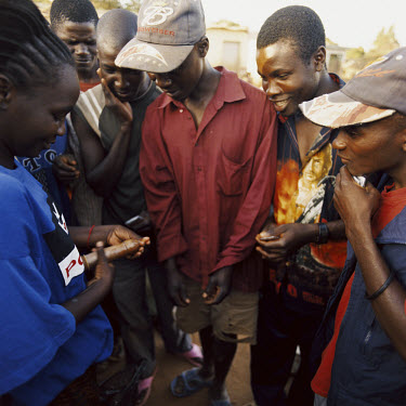 An aid worker demonstrates to a group of young men how to use a condom.
