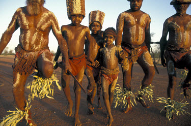 Painted with red ochre and decorated with leaves, Aboriginal elders teach the younger boys traditional ceremonial practices.