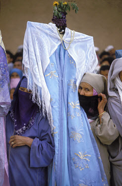 Women carry a dress with a head of flowers through a market in Marrakesh.