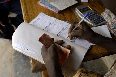 Elias Mohammed, Kuapa Kokoo's elected 'recorder', writes in the company log book before paying a farmer for his beans. Kuapa Kokoo is a cocoa farmers' co-operative with 45,000 members spread across th...
