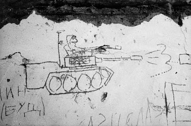 Scratched graffiti shows tanks at a local bus stop.
