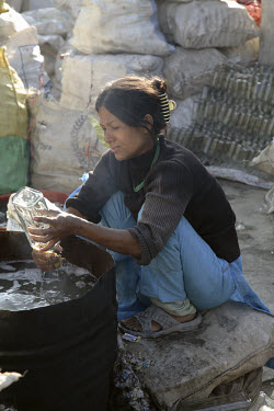 A woman washes bottles at a glass recycling business.
