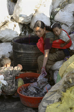 Woman with two young children washing bottles at a glass recycling business.