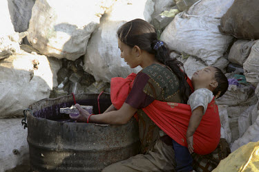 A young mother washes bottles at a glass recycling business.
