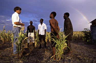 A rainbow arches over an international aid worker as he discusses future plans with local farmers.