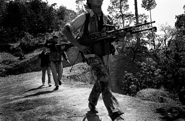 Maoist guerillas pass by a village in Rolpa District, one of the Maoist strongholds during the 1996 - 2006 civil war.