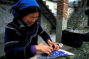 A Dai minority woman stitches some traditional embroidery during the winter months when there is little work to be done in the fallow rice fields.