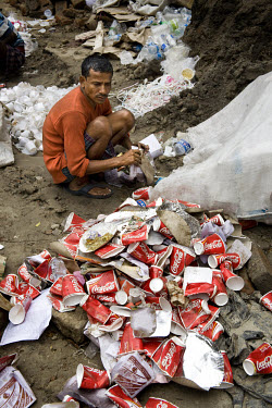 Coca-Cola drinks cups are amongst the rubbish at the back of a restaurant in Kolkata as a man collects paper and plastic for recycling.