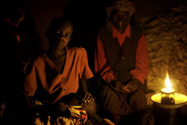 A family sits in their rural home lit by a paraffin lamp.