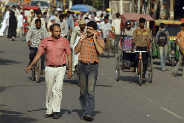 Middle class Indian men, one on a mobile phone, walking along one of the main streets/bazaars in the Old City area.