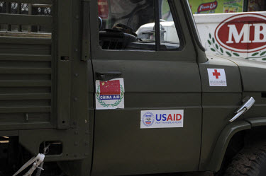 In the wake of Cyclone Nargis, an army truck sports various international donor logos including USAID and China Aid as it leaves the depot having collected donations from the airport. Cyclone Nargis h...