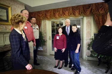 John McCain, Republican candidate for President, has his picture taken with the children of the owners of a house who held a party in his honour during the New Hampshire primary campaign.