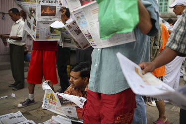 People reading newspapers in the early morning on the streets of Kathmandu.