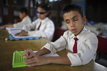 Student using a braille board at a school for blind children.