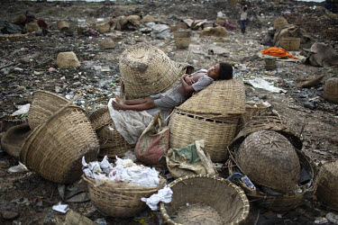 A child rests while collecting rubbish for resale. At the end of each day, he earns TK 55 to 70 (USD 1). The Matuail Dump is one of three waste sites in Dhaka, a city of over ten million people. On av...