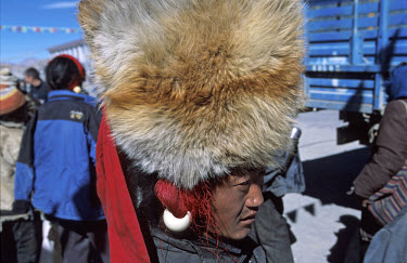 A Khampa man wearing a large foxskin hat along the main street in town of Tingri on the Tibetan Plateau. Tingri is a popular market town, and many travel in from the surrounding rural areas.