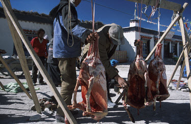 People check the quality of the meat being sold on the main street in Tingri on the Tibetan Plateau. The abatoir was in a tent around the corner. Tingri is a popular market town and many travel in fro...