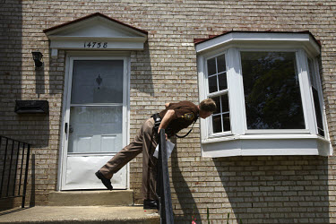 Deputy Rick Booth from the Manassas Sheriff Office in Virginia peers through the window of a foreclosed home. He found the house empty, but with the locks changed. The area is suffering from a major c...