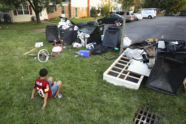 A young boy sits on the grass beside a pile of discarded things outside a foreclosed home in Manassas, Virginia. The area is suffering from a major collapse in the housing market following the subprim...