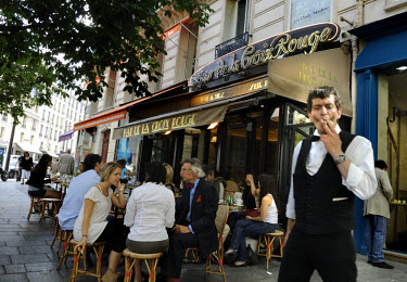 A waiter from a cafe in the fashionable Left Bank district of St Germain des Pres forced by new anti-smoking laws to take a quick cigarette break on the street, while his customers can still smoke on...