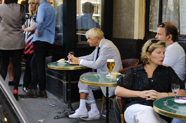Man sitting at an outdoor table at the famous Cafe de Flore in the fashionable Left Bank district of St Germain des Pres, once the 'living room' of Jean Paul Sartre.
