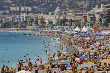 Tourists crowd the public beaches running along Nice's Mediterranean waterfront, with the distinctive dome of the luxury Negresco Hotel on the Promenade des Anglais behind. Nice is the largest city on...