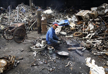 A worker uses a blow torch to cut up a gas canister at a recycling yard near Wenzhou. While some of the scrap material is collected from around the country, most is imported in bulk from developed cou...