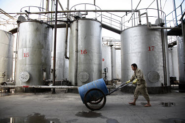A worker pushes a barrel past storage tanks at China Clean Energy Inc in Fuqing. The company recycles waste cooking oil products into precursor materials that will eventually make bio-desiel, epoxies,...