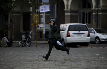 A police commando runs for cover as gunfire rains down from the Taj Mahal Palace Hotel, after multiple terrorist attacks were launched in Mumbai on 26/11/2008.