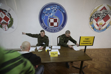 Privates Piotr Kolcz and Konrad Kosiol sit at the reception desk for new conscripts under a sign that reads ^Air Force^. This year's class of drafted recruits is the final one after 90 years of compul...
