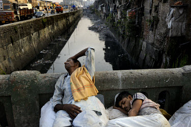 Tired porters taking a break at dusk, on a bridge over a polluted canal that crosses Mumbai's biggest slum, Dharavi, a thriving mix of poverty and enterprise that is home to over one million people.