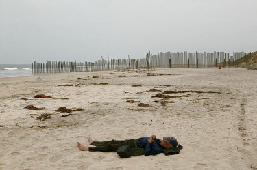 A migrant sleeps on the Playas de Tijuana which separates Mexico and the USA.